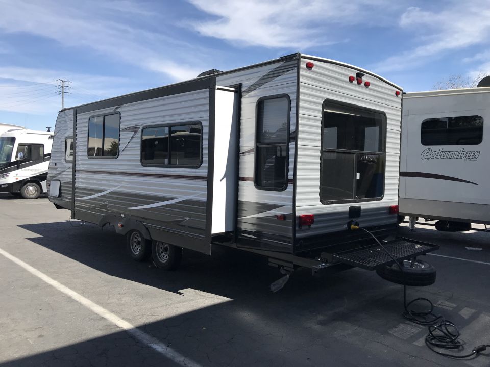 Gray and dark gray travel trailer with extended cargo rack and spare tire.