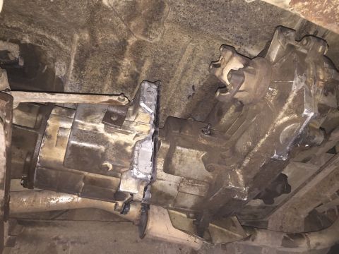 1984 Ford Bronco - This image shows the underside of a vehicle, focusing on the transmission and transfer case. The components appear heavily used and dirty,…