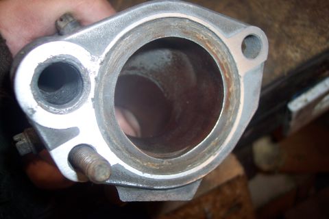 1995 Ford Bronco - A close-up view of a metal part, likely an intake manifold or exhaust component, showing internal wear and some rust around the edges. A bo…