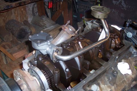 1995 Ford Bronco - A close-up view of a V8 engine block with the oil pan removed, showing the crankshaft, connecting rods, and oil pickup tube. The engine app…