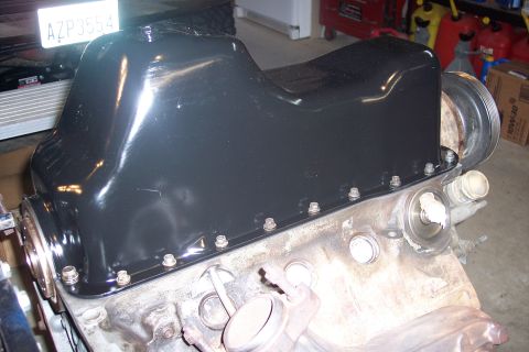 1995 Ford Bronco - A black painted oil pan is bolted onto the engine block of a vehicle, with a pulley visible on the right side.