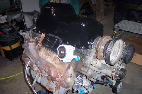 1995 Ford Bronco - A Ford V8 engine block is shown with a freshly painted black oil pan, exhaust manifold, and various pulleys attached to the front. The engi…