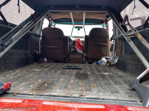 1989 Ford Bronco - The interior of a 1989 Ford Bronco, equipped with a roll cage and aftermarket seats, is shown from the rear cargo area.
