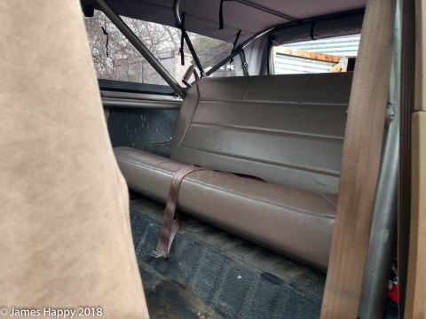 1989 Ford Bronco - Rear bench seat and roll cage visible inside a vehicle's interior.