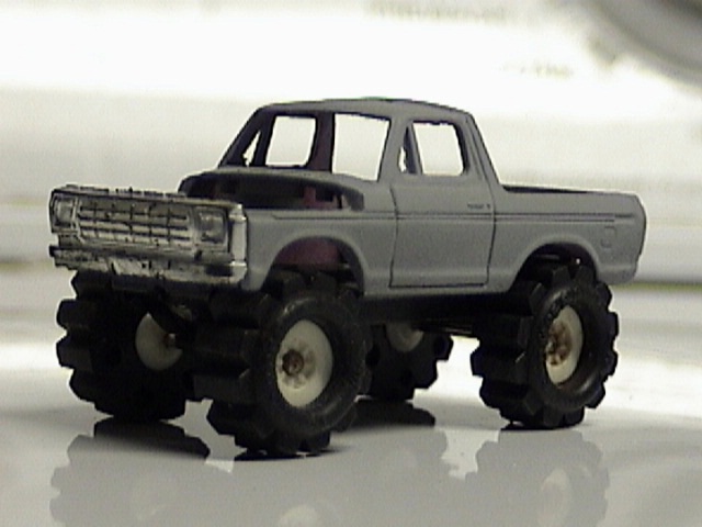 Gray toy monster truck with large tires, lifted suspension, and a prominent grille
