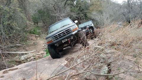 1995 Ford Bronco - Two off-road vehicles, a 1995 Ford Bronco and a Jeep Wrangler, navigate a steep, rocky trail.
