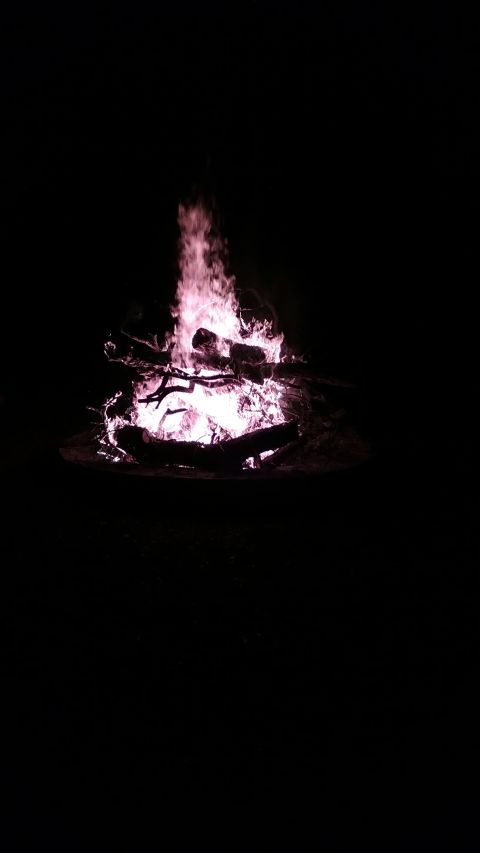 1995 Ford Bronco - A large bonfire burns brightly in the dark, with logs and branches consumed by the flames.