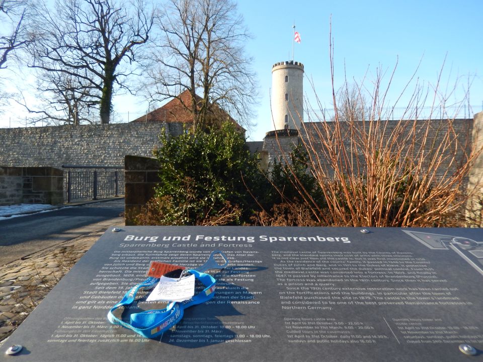Informational sign in foreground with fortress tower and stone wall in background