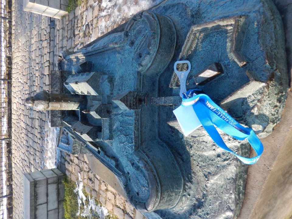 Bronze sculpture of buildings with a bottle opener and blue lanyard attached