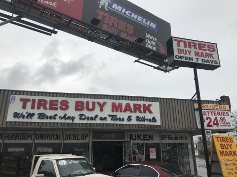 1997 Dodge 3500 - A white pickup truck is parked in front of a "Tires Buy Mark" store.