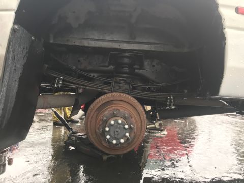 1997 Dodge 3500 - The rear suspension and axle of a truck are visible, with a jack supporting the vehicle.