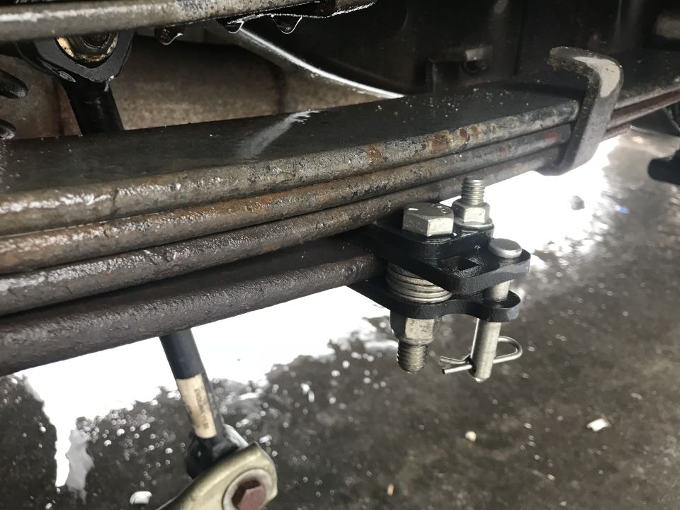 Leaf spring assembly with U-bolt and clamp, showing rust and water droplets