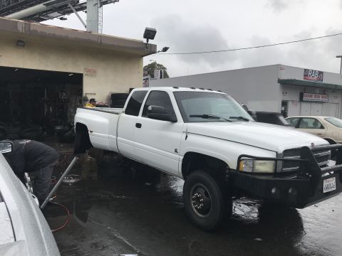 1997 Dodge 3500 - White 1997 Dodge 3500 dually pickup truck is being serviced outside a garage.