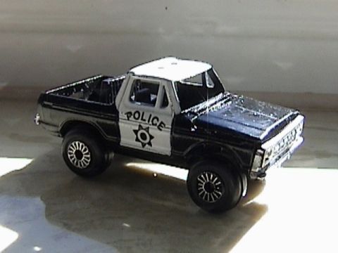 1979 Ford Bronco - A black and white toy police pickup truck is shown from a 3/4 front angle.