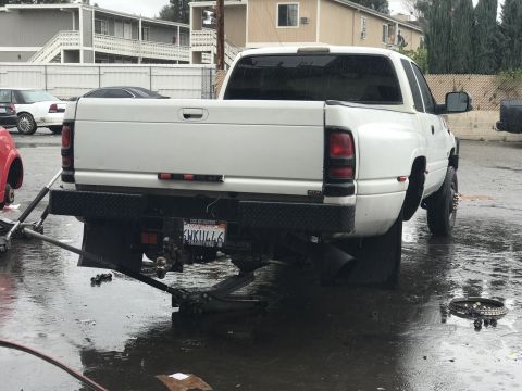 1997 Dodge 3500 - A white pickup truck is being worked on, with its rear end elevated by hydraulic jacks.