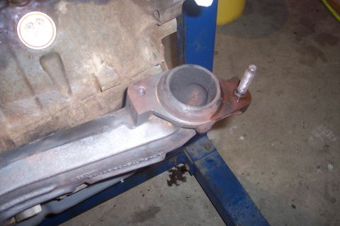 1995 Ford Bronco - Close-up of an exhaust manifold, likely removed for repair or replacement, resting on an engine stand.