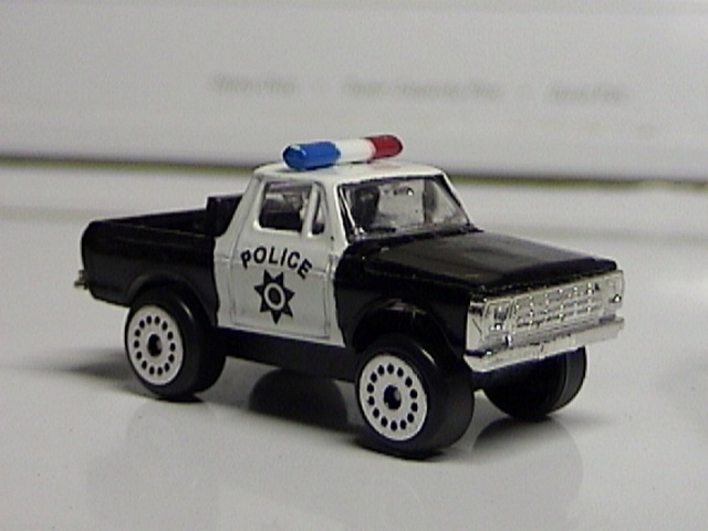 Black and white police pickup truck with "POLICE" text and a star badge