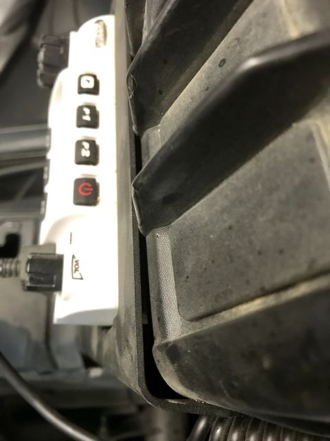 1988 Ford Bronco - Close-up of an aftermarket electronic device with volume control and function buttons inside a vehicle's cabin.