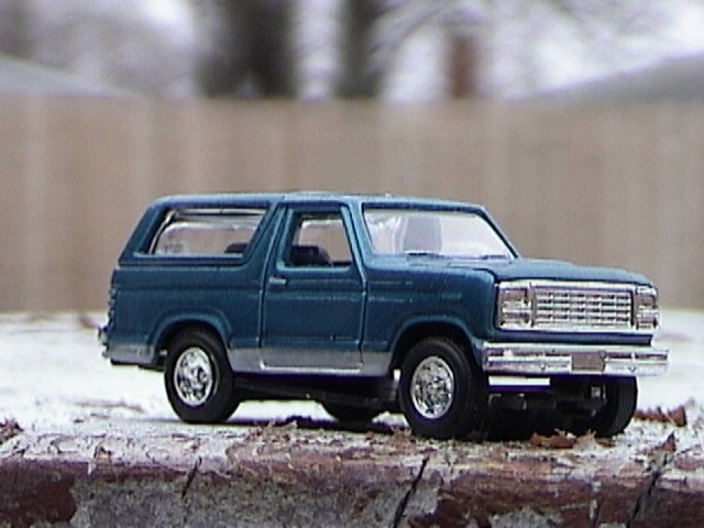 1979 Ford Bronco toy car, blue with silver trim, parked on a textured surface