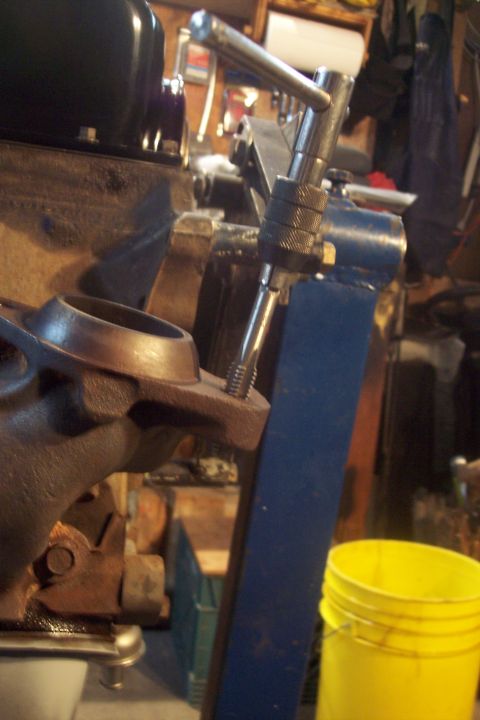 1995 Ford Bronco - A tap tool is used on an engine component in a workshop setting, with a yellow bucket visible.