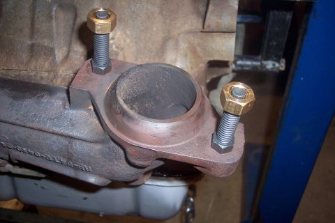 1995 Ford Bronco - Close-up of exhaust manifold bolts with brass nuts, attached to an engine block.