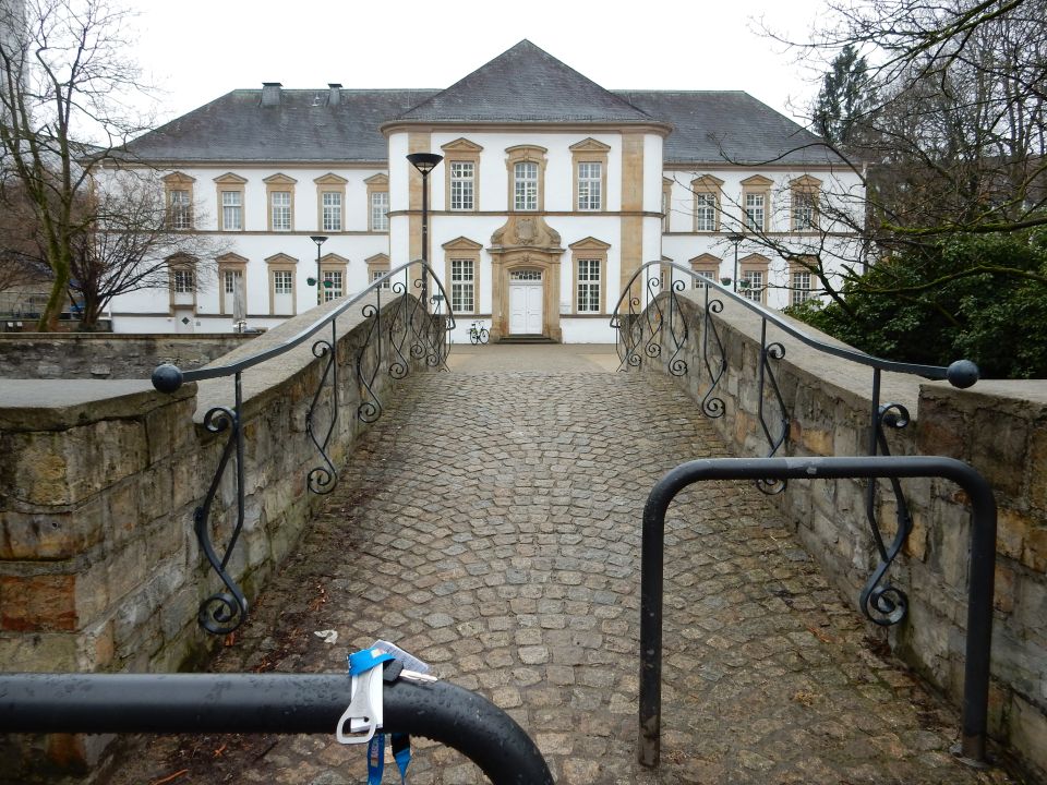Stone bridge leads to a large white building with many windows