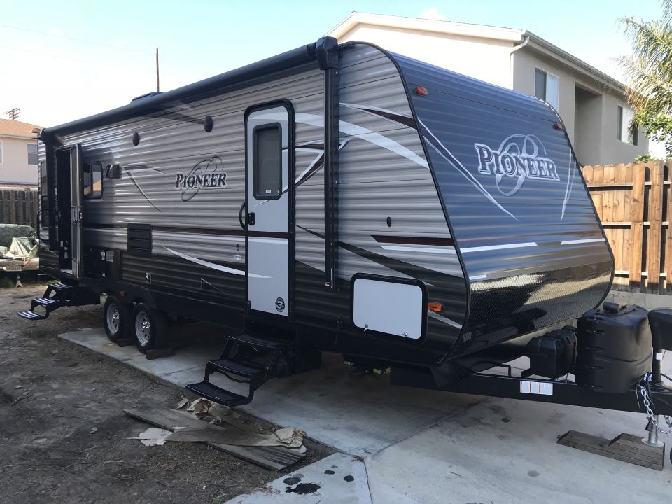 Travel trailer with 'PIONEER' branding, parked on a concrete pad
