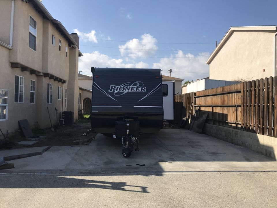 Front view of a dark gray Pioneer travel trailer parked in a driveway