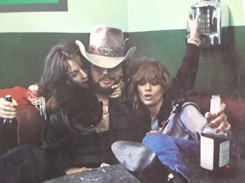 1994 Ford Bronco - A man in a cowboy hat is seated between two women, all appearing to be holding drinks.