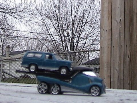 1979 Ford Bronco - A blue 1978 Ford Bronco is transported on a unique trailer, with a wooden fence and bare trees in the background.