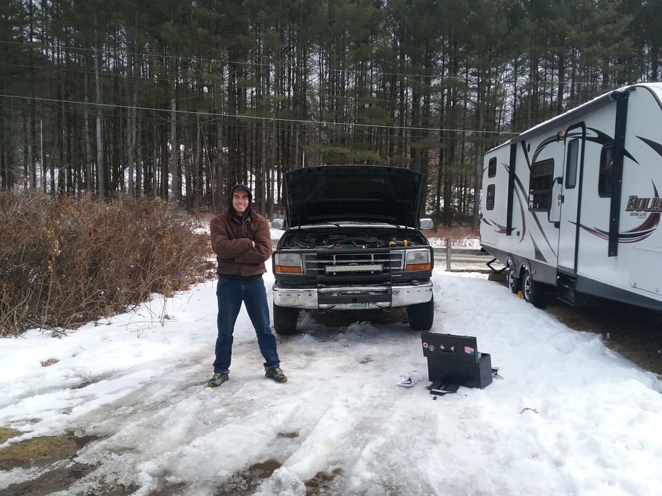 Ford F-Series truck with hood open, parked in snow next to a trailer