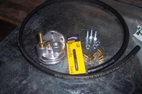 1995 Ford Bronco - An oil cooler adapter with brass fittings, a Gates transmission oil cooler hose, and assorted hardware are laid out on a metal surface.
