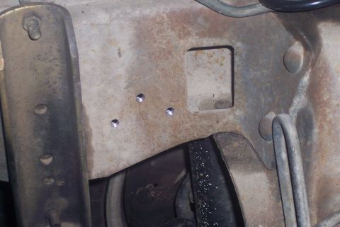 1995 Ford Bronco - Detail shot of a vehicle's rusty frame, newly drilled holes and a square opening.