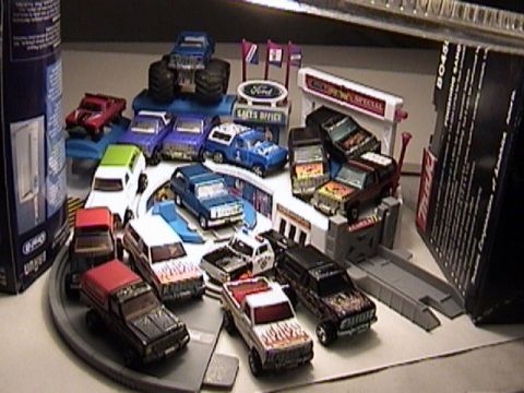 1979 Ford Bronco - A variety of toy trucks and SUVs are displayed around a Ford dealership playset.