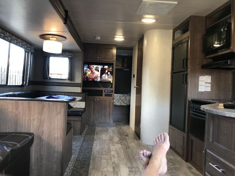 2018 Yugo GV - The interior of a recreational vehicle shows a living area with a couch and television, leading to a kitchen space.