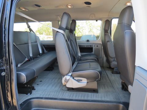 1996 Ford Bronco - Interior view of a van showing multiple rows of black seats with seatbelts and grey carpeting.