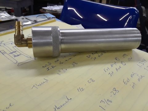 1994 Ford Bronco - A metal canister with brass fittings sits on a surface covered in handwritten notes and technical diagrams.