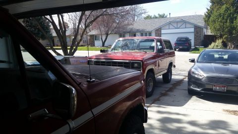 1985 Ford Bronco - This red SUV features a boxy body style and a prominent chrome grille, suggesting an early 1980s model.