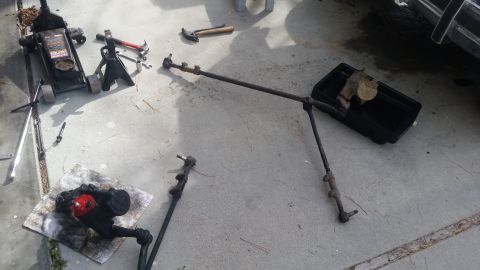 1985 Ford Bronco - Disassembled steering components laid out on a concrete surface with various tools nearby.