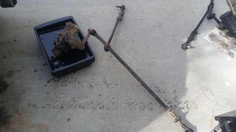 1985 Ford Bronco - Steering linkage and gearbox removed from a vehicle, placed on concrete.