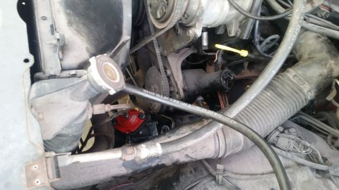 1985 Ford Bronco - The engine bay shows various mechanical parts and hoses, with a red component visible near the radiator.