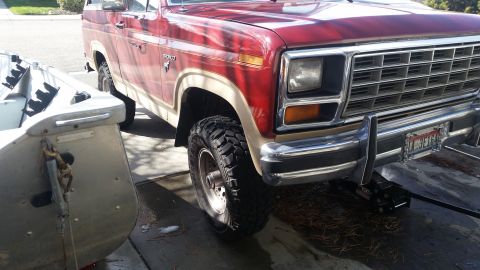 1985 Ford Bronco - This 1985 Ford Bronco features a two-tone red and tan paint scheme and aggressive off-road tires.
