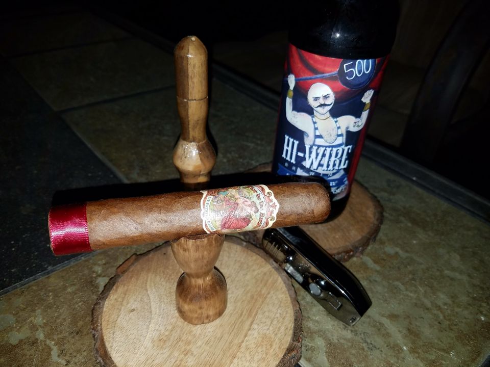 Cigar on a wooden stand next to a bottle of Hi-Wire 500 beer and a lighter