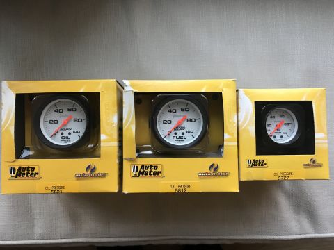 1989 Ford Bronco - Three Auto Meter gauges, including two oil pressure and one fuel pressure, are displayed in their original yellow packaging.