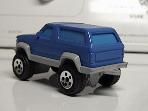 1979 Ford Bronco - A blue toy SUV sits on a reflective surface, its rear three-quarter view captured in the photo.