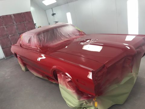1968 Mercury Cougar - A freshly painted red muscle car is being prepped for final assembly inside a professional paint booth.