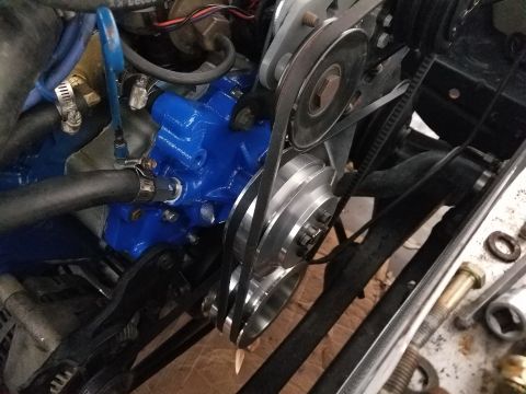 1976 Ford Ranchero - Close-up view of engine components, including a bright blue water pump and various belts and pulleys.