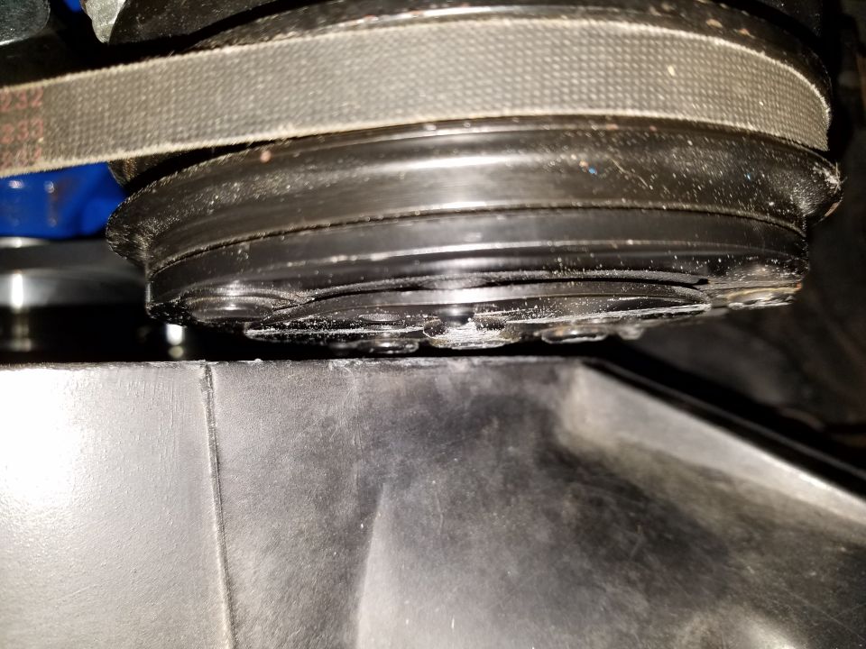 Close-up of a serpentine belt and pulley system, possibly an AC compressor clutch