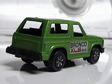 1979 Ford Bronco - A green toy Bronco XLS 4x4 is shown from a rear three-quarter angle against a blurred background.