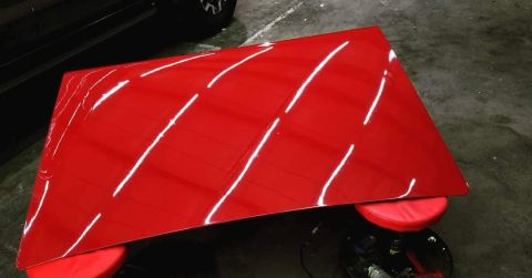 1967 Ford Galaxie - A red car hood is shown from an elevated angle, reflecting overhead lights.